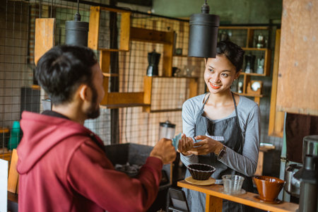 transaction between the female barista and the male customer at the cashier deskの写真素材