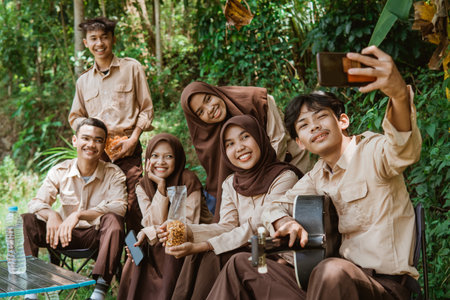 group of youth scouts taking selfies together using a cellphone camera while campingの写真素材