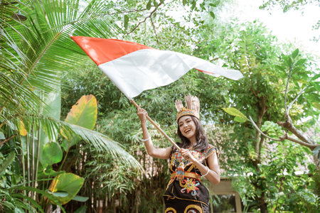 asian woman in king bibinge waving the stick of indonesian flag at the nature and smilingの写真素材