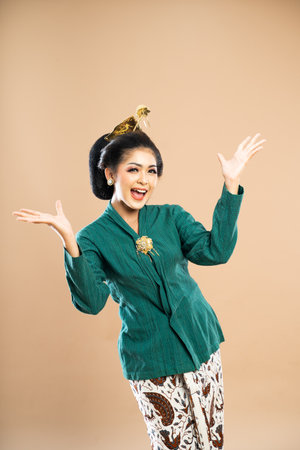 asian woman in green kebaya standing with wide smile and opening her both hands on isolated backgroundの写真素材