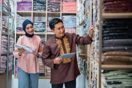 male and muslim Female worker checking product quality and stock at fashion shop warehouse holding tabletの写真素材