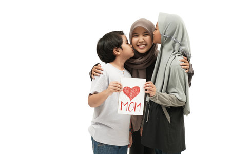 children are giving a suprise card to their mother during mothes day. happy muslim asian mother with son and daughterの写真素材