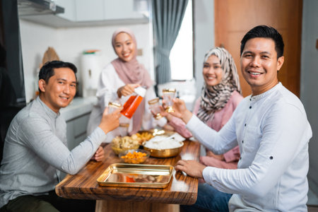 muslim woman serving drink for her friend and family at home having dinner togetherの写真素材