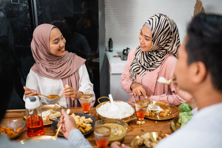 portrait of two muslim girl friend chatting while having iftar dinner at homeの写真素材