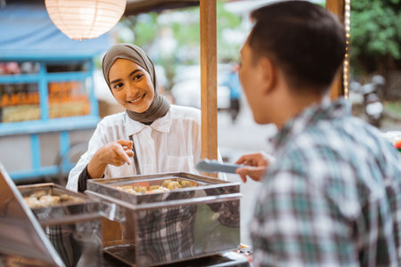 man sells various kinds of dumpling food with a cart on the side of the roadの写真素材