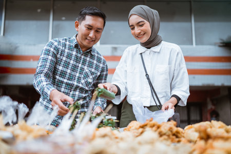 beautiful muslim couple are shopping in a food stall or street vendor during ramadanの写真素材