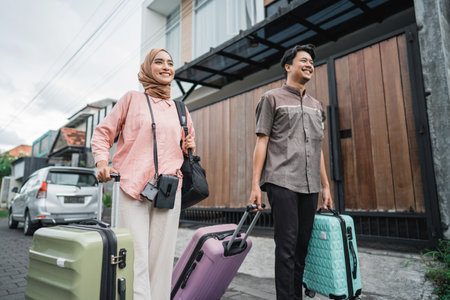 asian muslim couple with suitcase prepare to go. concept of man and woman travelling for eid mubarak celebrationの写真素材