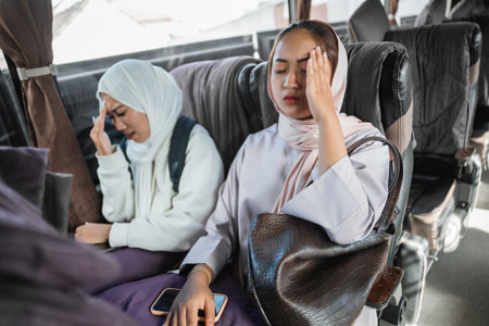 portrait of two muslim woman feeling unwell while sitting inside the busの写真素材
