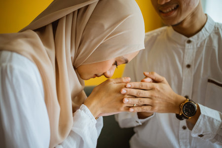 asian muslim wife kissing husbands hand as a sign of apologies during Eid celebrationの写真素材