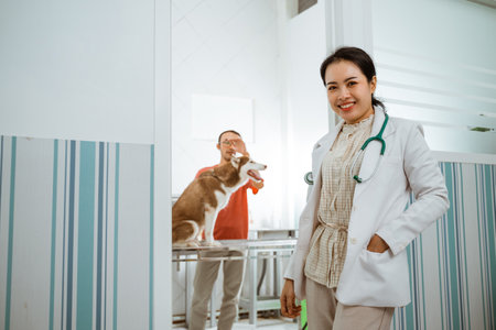 a female vet lean against the door with the brown siberian dog and its owner at the backgroundの写真素材