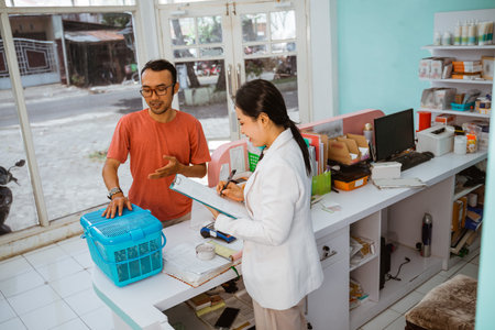 a male pet owner explain the condition of his pet to the female vet, against the glass wallの写真素材