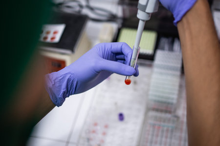 Doctors hand using an eyedropper puts a blood sample into a small tube in the laboratory