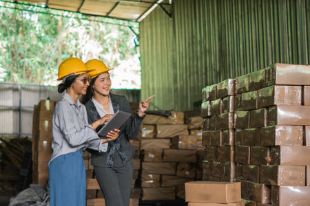 two Asian women factory employees work on a laptop in the goods warehouseの写真素材