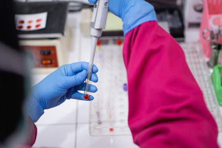 hands with rubber gloves using a pipette when inserting blood samples into a small tube for testing in the laboratoryの写真素材