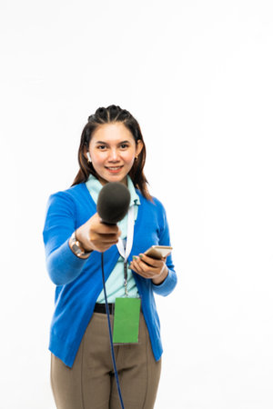 a female reporter in blue shirt and blue cardigan standing with phone at her hand and hand over a black microphoneの写真素材