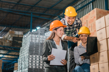 two female and one male factory employees work on a laptop in the goods warehouseの写真素材
