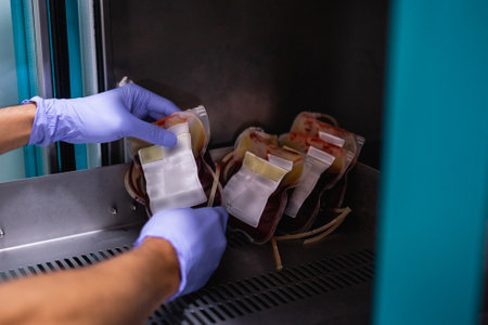 close up hand with rubber gloves holding blood bag in storage cabinetの写真素材