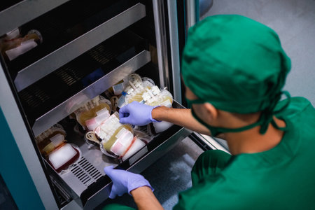 doctor in uniform with rubber gloves removes blood bag from storage cabinet shelfの写真素材