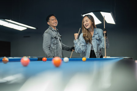 female pool player put her hand on the shoulder of the male player while standing beside the poolの写真素材