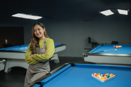 beautiful bar worker smiling while standing crossing hands on the pool at the biliard studioの写真素材