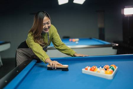 female pool table worker helps player arranging the balls with triangle rack