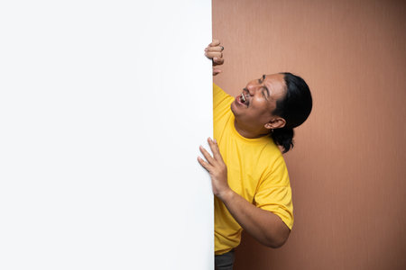 old asian man standing behind and holding empty white board or free space in plain background isolatedの写真素材