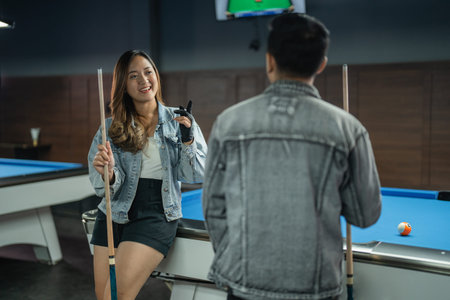 female pool player put her hand on the shoulder of the male player while standing beside the pool