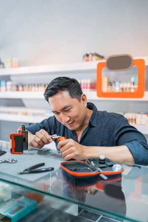 male shopkeeper changing the vape cotton coil seriousely at the vape storeの写真素材