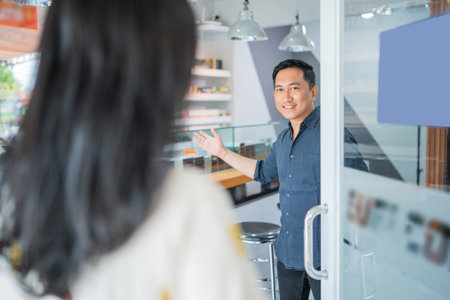 male vape seller wellcoming the female customer to entering the vape storeの写真素材