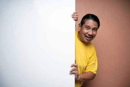 old asian man standing behind empty white board or free space for advertisement or billboard in plain background isolatedの写真素材