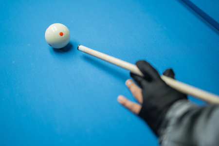 the hand of the male player with black glove poking the white ball using the cue stickの写真素材
