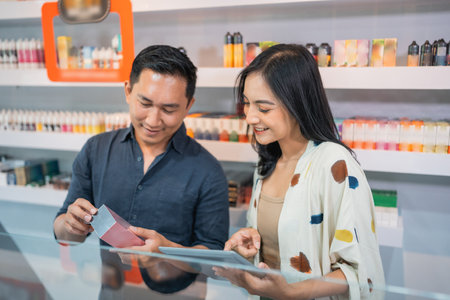 couple of shopkeeper using the digital tablet while observing the vape mode inside the display tableの写真素材