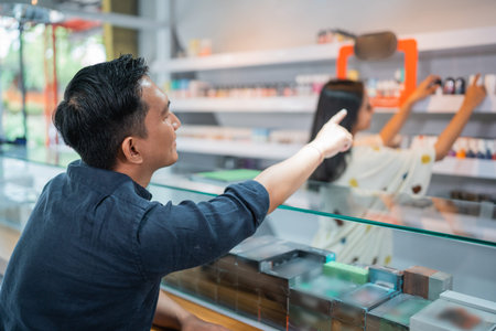 male customer pointing on the liquid arranged at the store shelf to guiding the sellerの写真素材