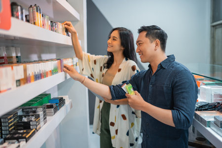 couple of vape seller observing the liquid from the shelf at the storeの写真素材