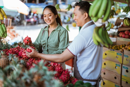 female customer smiling while helped by the male employee to choosing the dragon fruits at the fruit shopの写真素材