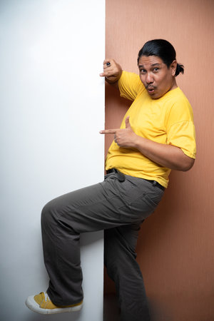 old asian man standing beside empty white board with poiting gesture fullbody view in plain background isolatedの写真素材