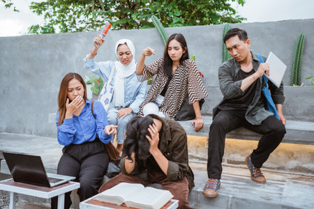 Some students bully their male group mates while sitting together outside the campusの写真素材