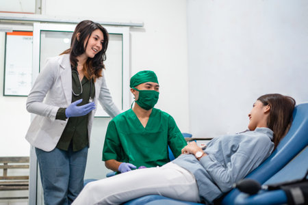 a woman donor lies down during a blood transfusion with two doctors in the blood transfusion roomの写真素材