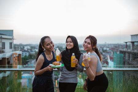 three smiling young women in sportswear holding bottles after exercise
