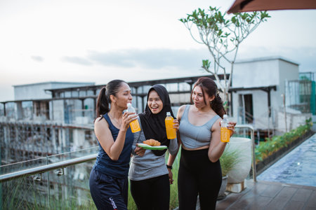 three Asian girls jokingly wear workout clothes while drinking after exerciseの写真素材