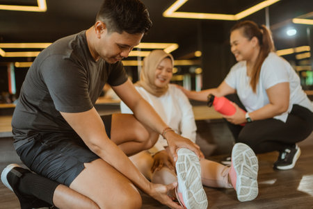 asian male instructor helping trainee with sprained ankleの写真素材