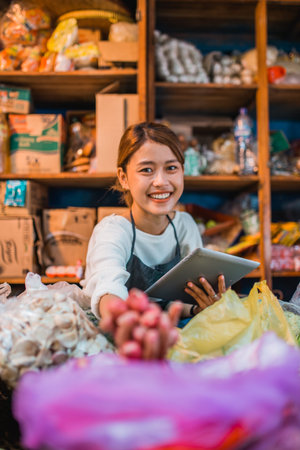 potrait of female asian green grocery seller checking vegetables supplies