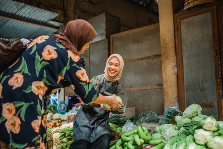 happy asian green grocery seller helping her customer choosing vegetableの写真素材