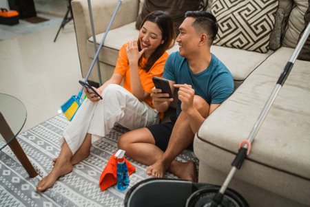 asian couple joking around after cleaning the houseの写真素材