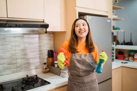 woman in apron and gloves standing in the kitchenの写真素材