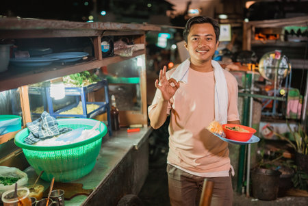 asian male seller holding a bowl of noodle with okay hand gestureの写真素材