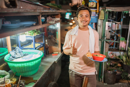 asian male seller holding a bowl of noodle with thumb up gestureの写真素材