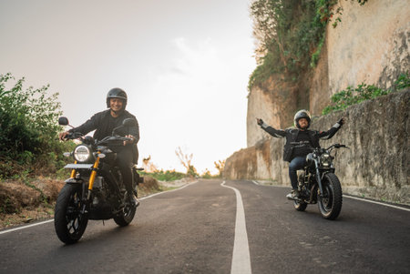asian riders doing hand off steering while riding motorbikeの写真素材