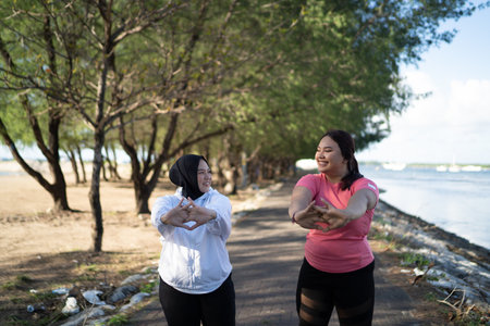 two asian women warming up together before runningの写真素材