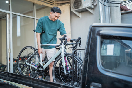 man removing bicycle from pickup car at a bike shop backgroundの写真素材